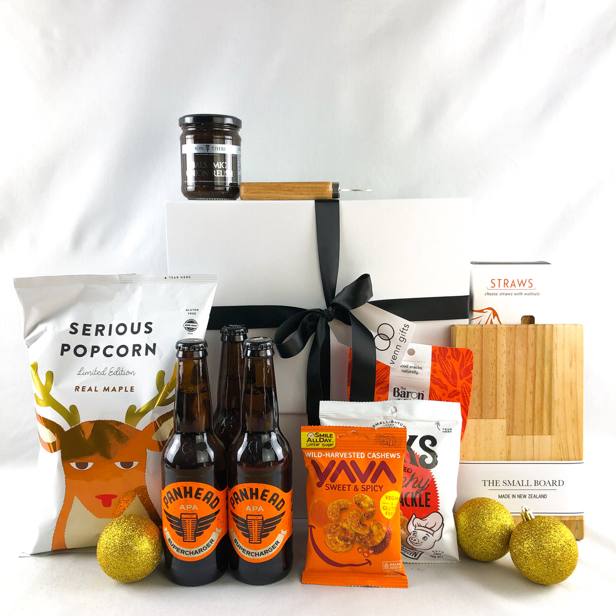 christmas snacks, treats, beers in front of a white giftbox with black ribbon by Venn Gifts
