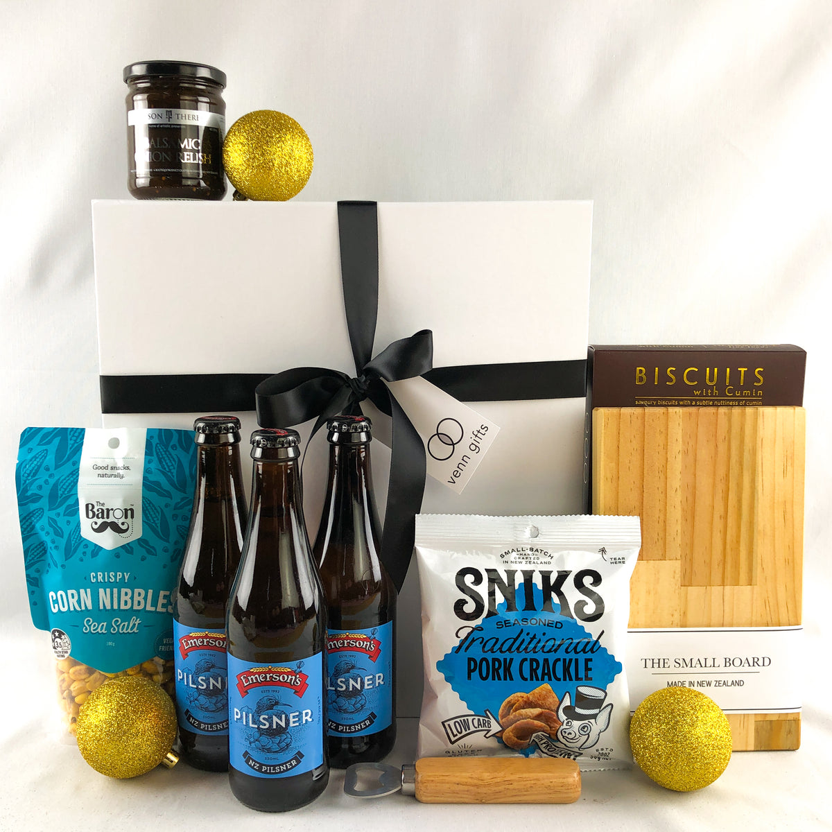 beers, treats and snacks in front of a white gift box with a black ribbon by Venn Gifts.