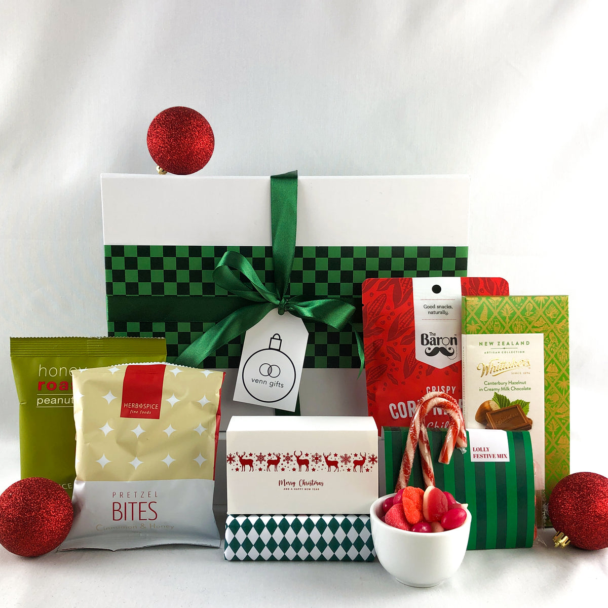 christmas treats in red and green in front of a white giftbox with green ribbon by Venn Gifts