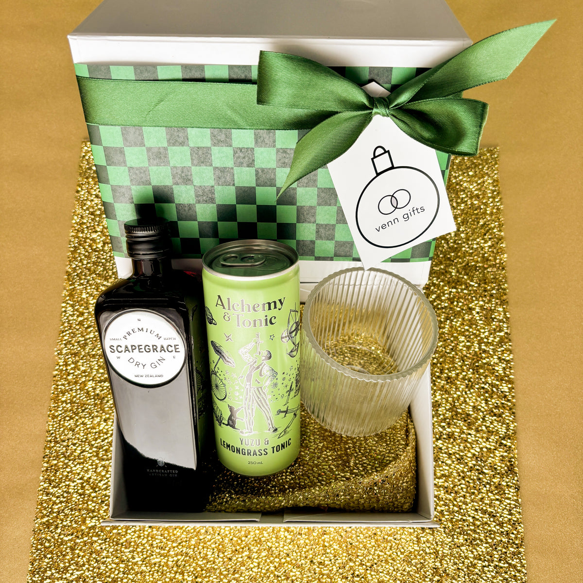 Scapegrace, Alchemy & Tonic 7 reeded glass in front of a white giftbox with green ribbon against a gold background by Venn Gifts.