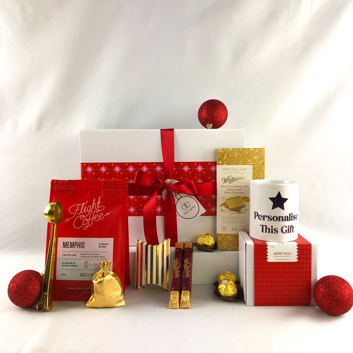 Personalised coffee mug and flight coffee with chocolates and gold small gifts in front of a white giftbox with red ribbon by Venn Gifts